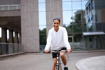 Pleased african american woman looking at camera while cycling outdoors 