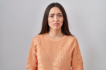 Obraz premium Young brunette woman standing over white background depressed and worry for distress, crying angry and afraid. sad expression.