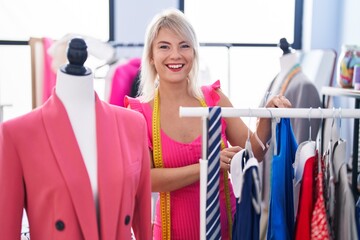 Naklejka na ściany i meble Young blonde woman tailor smiling confident holding clothes on rack at gaming room