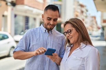 Man and woman mother and daugther using smartphone at street