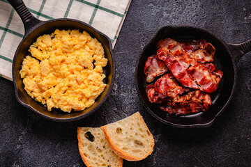 Cooked scrambled eggs and fried bacon in portion pans