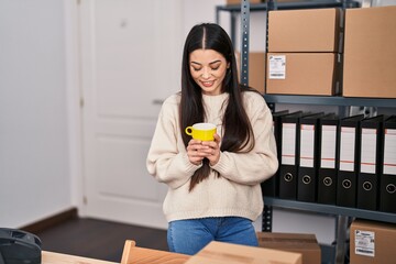 Young beautiful hispanic woman ecommerce business worker drinking coffee at office