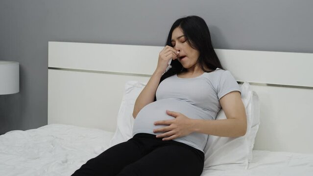 pregnant woman stuffy nose, sneezing, sore throat on a bed. flu during pregnancy