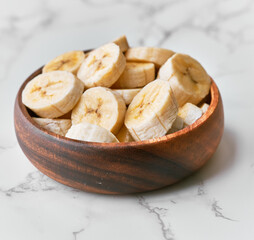 Photo of banana slices in a bowl on a marble table