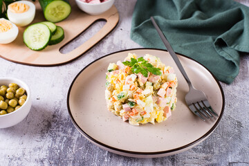 Traditional Russian Olivier salad of boiled vegetables and sausages on a plate on the table