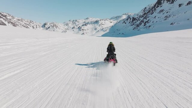 Woman riding snowmobile through arctic snow