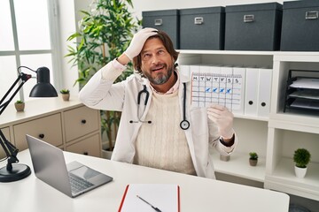 Fototapeta premium Handsome middle age doctor man holding holidays calendar stressed and frustrated with hand on head, surprised and angry face