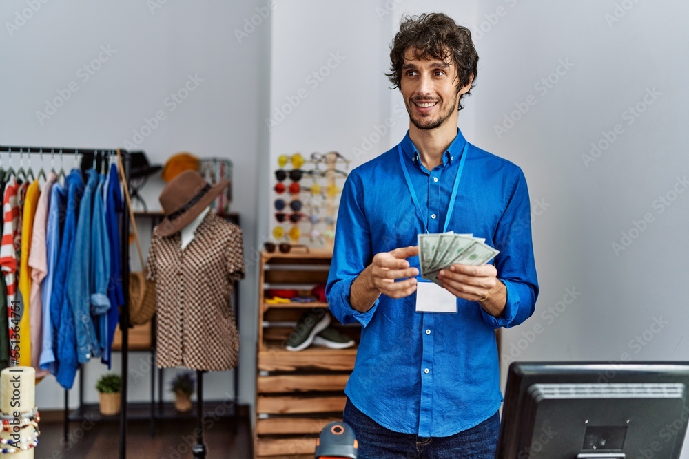 Sticker young hispanic man counting dollars working at clothing store