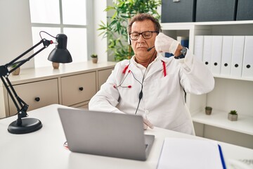 Senior doctor man working on online appointment strong person showing arm muscle, confident and proud of power