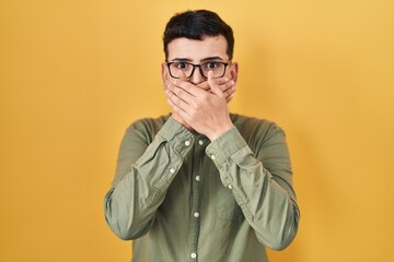 Obraz premium Non binary person standing over yellow background shocked covering mouth with hands for mistake. secret concept.