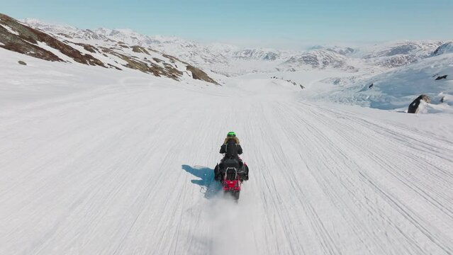 Woman snowmobiling through arctic tundra