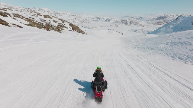 Woman snowmobiling through arctic snow