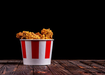 background, night, darkness. shot in a dark key. Chicken wings and barbecue legs in a bucket on a...
