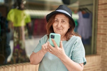 Senior woman smiling confident using smartphone at street