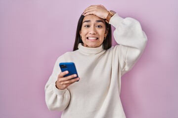 Young south asian woman using smartphone stressed and frustrated with hand on head, surprised and angry face