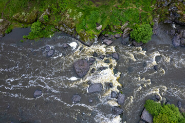 photo from a drone on a part of a mountain river, grass and stones along the banks