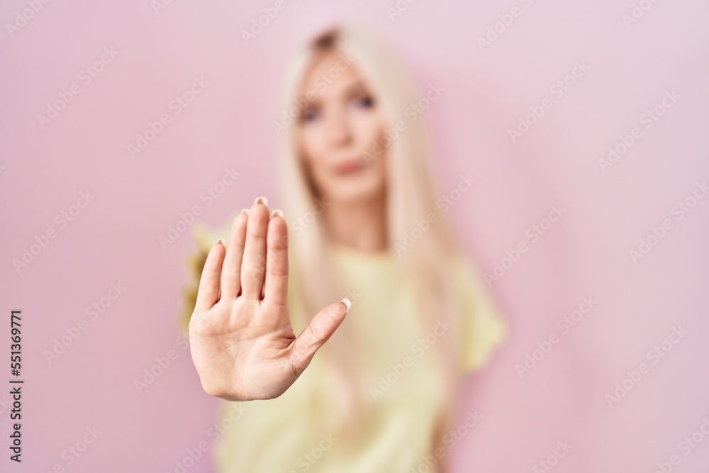 Sticker caucasian woman standing over pink background doing stop sing with palm of the hand. warning express