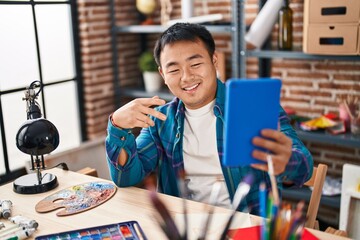 Young chinese man artist having video call at art studio