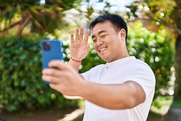 Young chinese man smiling confident having video call at park