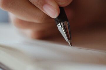 Female hand close-up writes with a pen in a blank notebook.she writing a daily lifetime.Business...