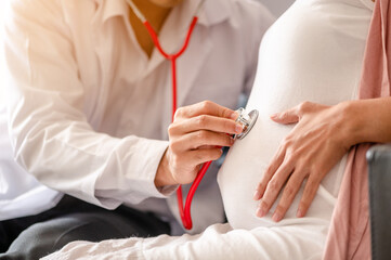 Happy pregnant woman visit gynecologist doctor at hospital or medical clinic for pregnancy consultant. Doctor examine pregnant belly for baby and mother healthcare check up.Mature male gynaecologist - obrazy, fototapety, plakaty