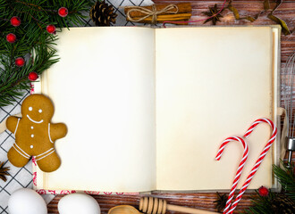 Vintage recipe book, baking ingredients and Christmas decor on the wooden table. Baking for Christmas. Close-up. Top view. Copy space.