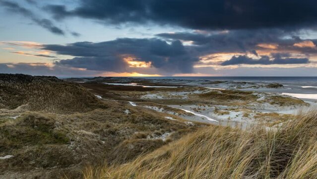 Time lapse Amrum island, Germany: sun rays emerging through the dark storm clouds at the beach of Amrum. Sunset is obscured by a thick cloud front announcing bad weather