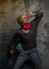 Fotobehang Dirty alcoholic male with vodka bottle near old stone wall © luzkovyvagon.cz