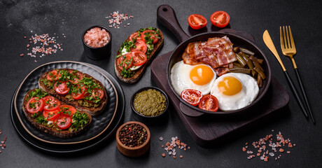 Tasty breakfast consists of eggs, bacon, beans, tomatoes, with spices and herbs