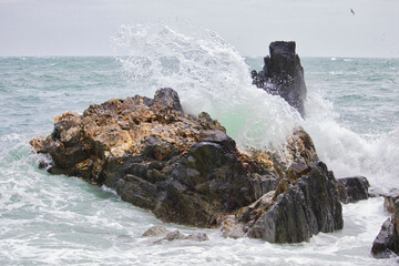 ocean wave breaking on a big rock