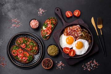 Tasty breakfast consists of eggs, bacon, beans, tomatoes, with spices and herbs