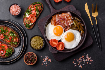 Tasty breakfast consists of eggs, bacon, beans, tomatoes, with spices and herbs