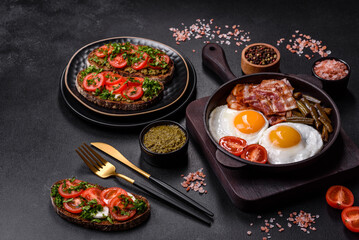 Tasty breakfast consists of eggs, bacon, beans, tomatoes, with spices and herbs