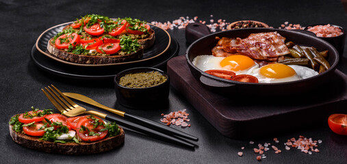 Tasty breakfast consists of eggs, bacon, beans, tomatoes, with spices and herbs