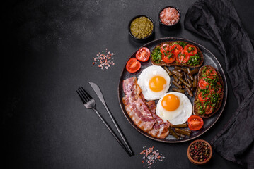 Tasty breakfast consists of eggs, bacon, beans, tomatoes, with spices and herbs