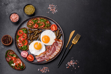 Tasty breakfast consists of eggs, bacon, beans, tomatoes, with spices and herbs