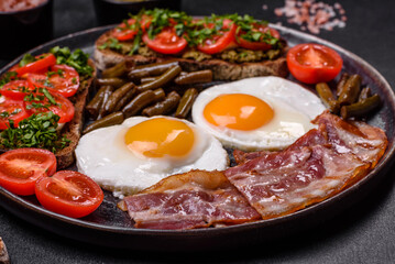 Tasty breakfast consists of eggs, bacon, beans, tomatoes, with spices and herbs