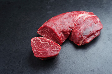 Raw Italian chianina beef fillet steak offered as close-up on a rustic black board with copy space