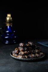 Dates fruit on oriental plate on dark background. Dried organic Superfood