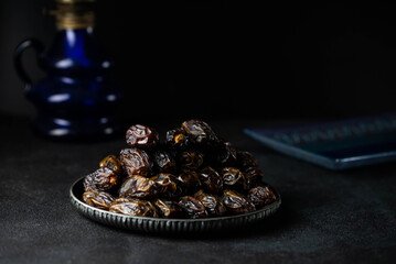 Dates fruit on oriental plate on dark background. Dried organic Superfood
