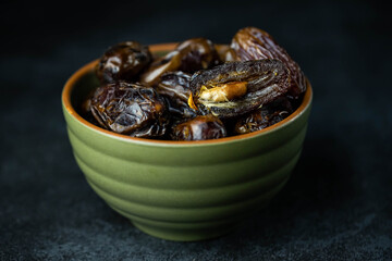 Dates fruit in bowl on dark background. Dried organic Superfood.