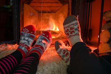 Fototapeta na wymiar Family in Christmas socks near fireplace. Mother; father and child having fun together. People relaxing at home. Winter holiday Xmas and New Year concept