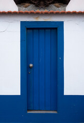 Blue door in a small seaside building with white walls and orange roof, retro postcard vibes