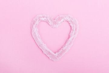 Frame of fluffy fur heart on a pink background. The concept of Valentine's day, love, dating and wedding. Minimalism, background, monochrome.