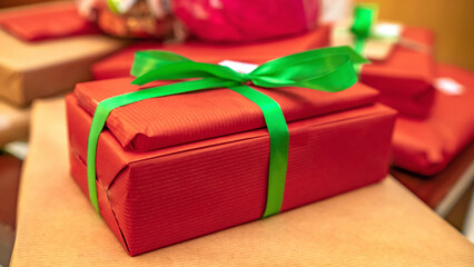 czerwony prezent z zieloną wstążką na tle innych prezentów 
