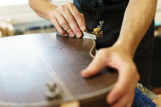 Unrecognizable male luthier crafting Spanish flamenco guitar