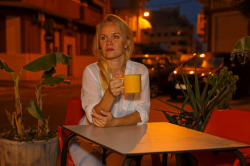 Pretty woman drinks tea or coffee in a cafe