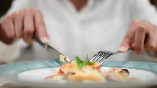 Lunch break female hands cutting food in a plate holding a metal fork lunch in a restaurant, Ready dish in a plate, Man having lunch at a restaurant table
