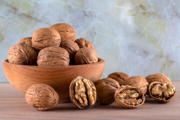 Peeled walnuts and whole walnuts in wooden bowl
