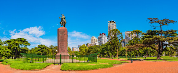 Panoramic cityscape view over green city park with exotic trees and monument of Juan Manuel de...